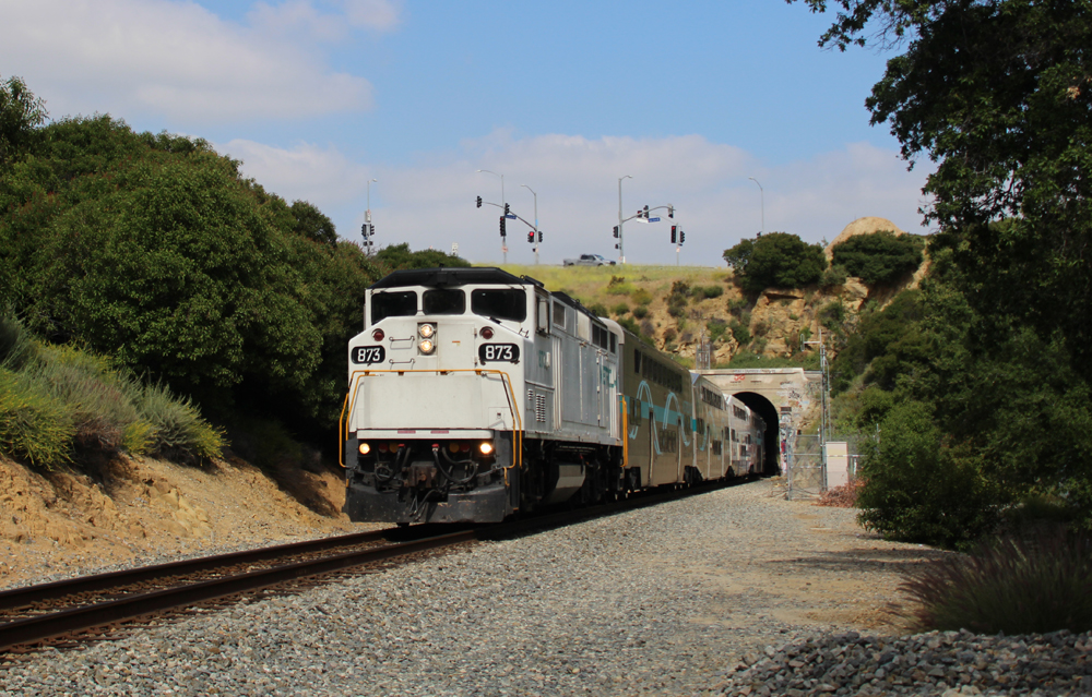 Commuter train with white locomotive emerges from tunnel