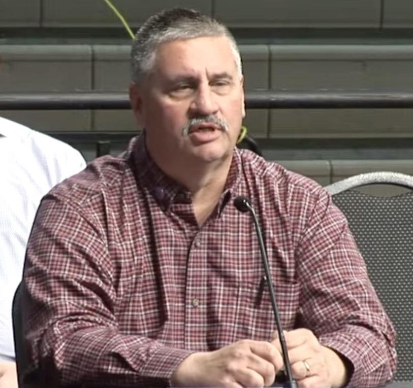 Man in checked shirt speaking into microphone