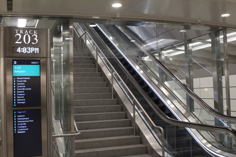 Escalator and stairs next to sign for train departure