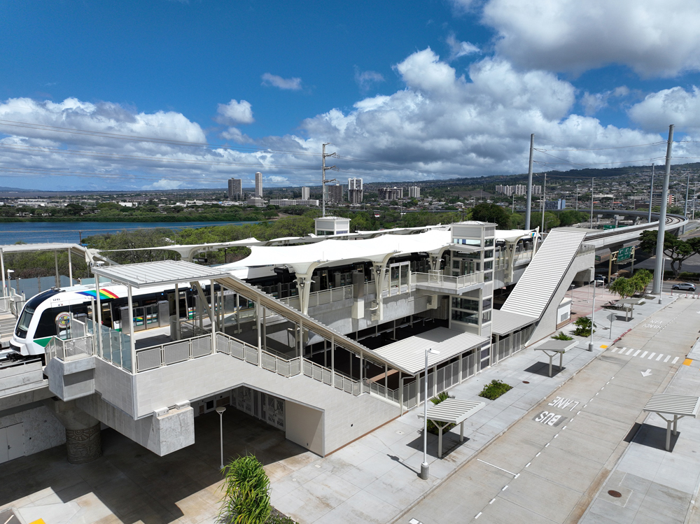 Light rail train at elevated station with city in distance