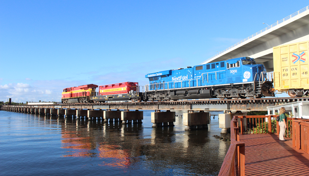Freight train with two locomotives and LNG tender crossing bridge