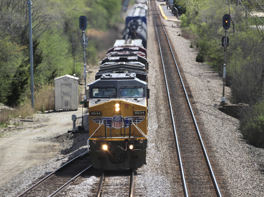 Yellow locomotive leading freight train in nose-on view from bridge