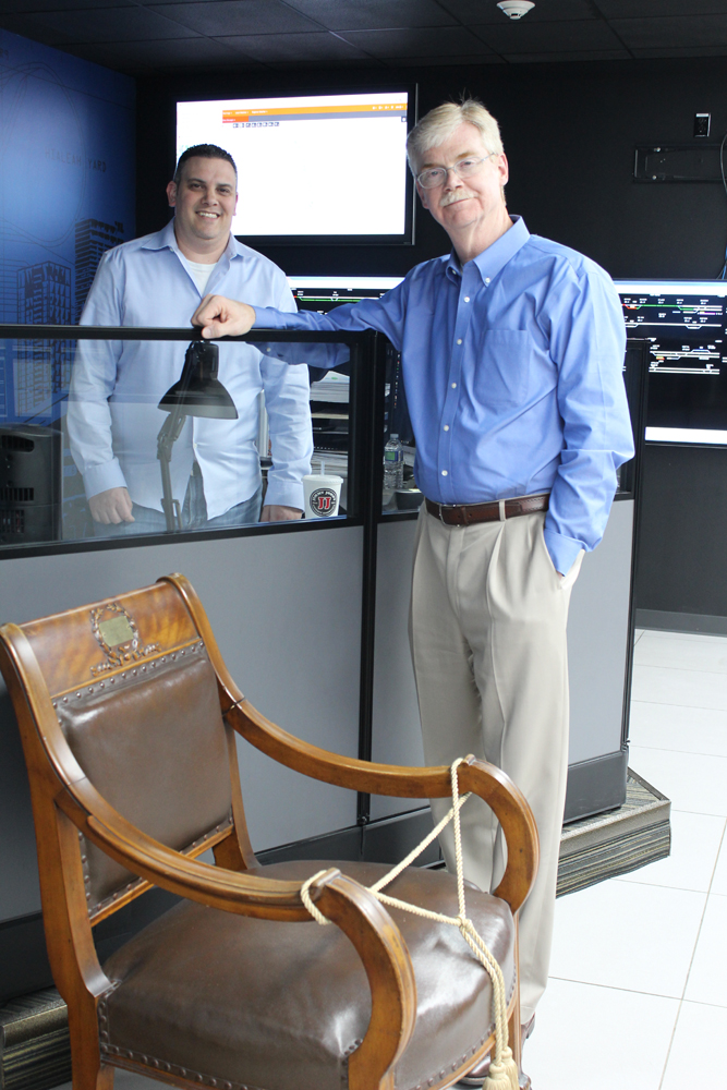 Two men posed near antique chair