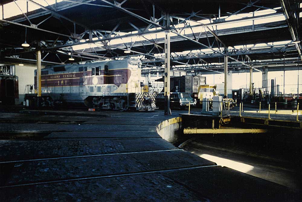 Gray-and-maroon diesel Algoma Central locomotives inside shop