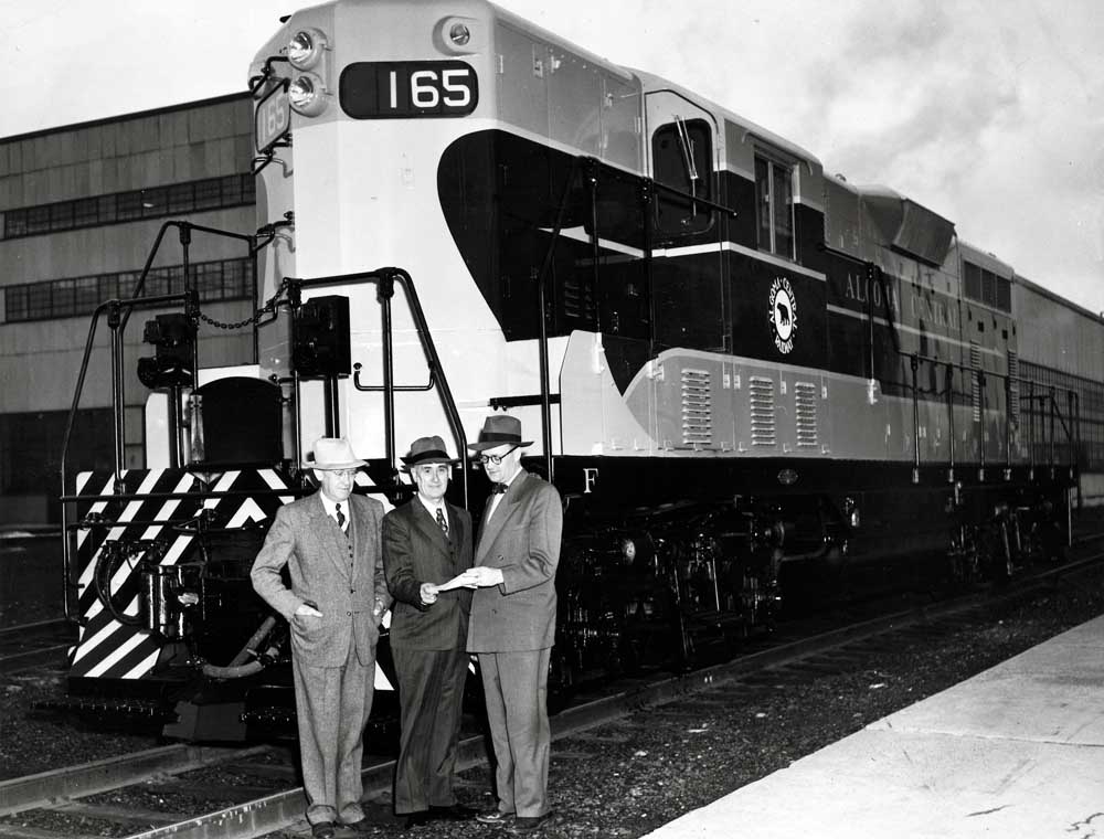 Men stand in front of diesel Algoma Central locomotives