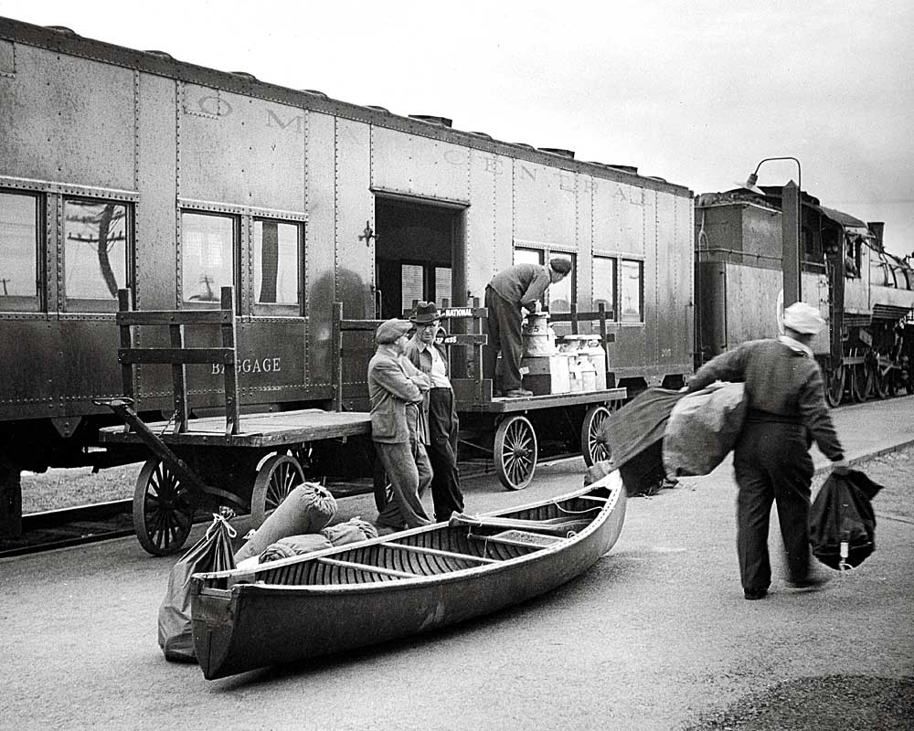 Men load odd-sized baggage and a canoe onto Algoma Central Railway passenger train