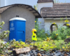 Playmobil figure with arms up next to a model outhouse