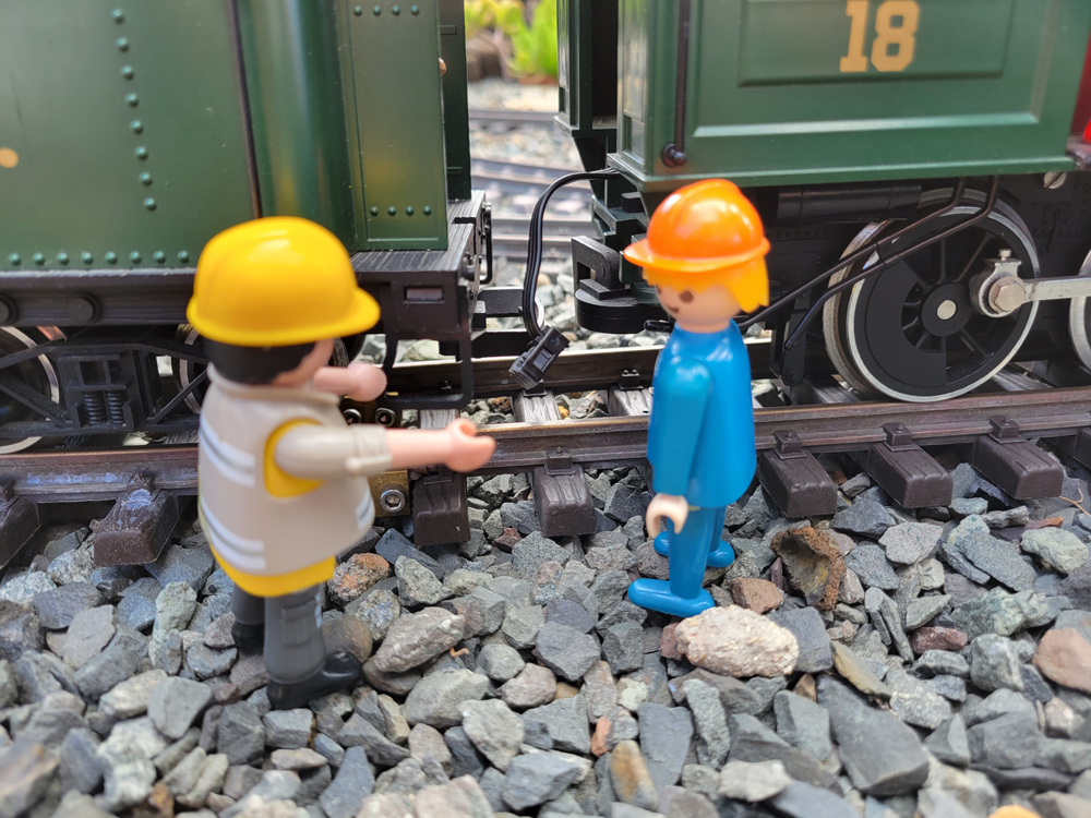 two figures next to a locomotive and tender