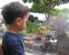 Playmobil and kids in the garden railway: child watching train on garden railway