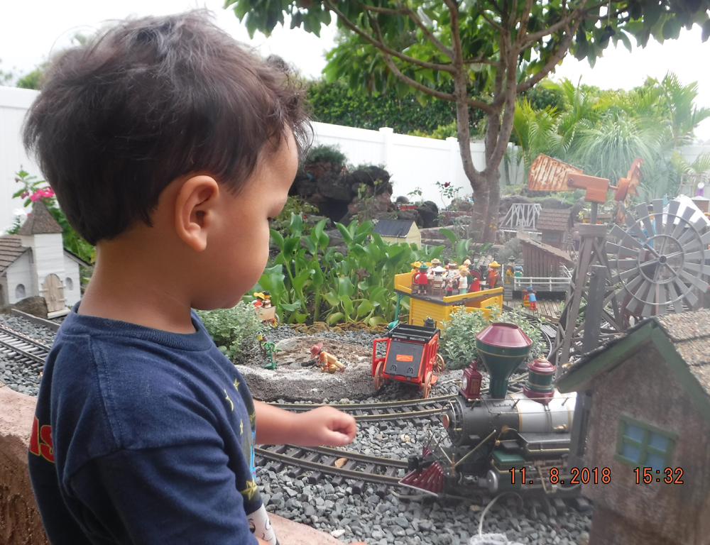 Playmobil and kids in the garden railway: child watching train on garden railway