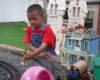 boy in red shirt with overalls places signal on garden railway