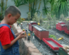 child plays with figures next to garden railway
