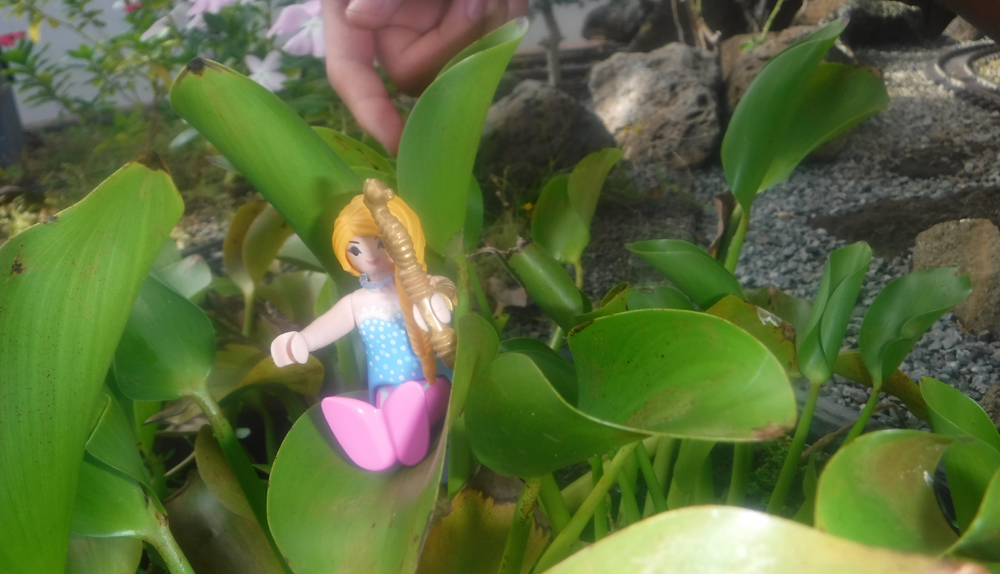 a mermaid figure sitting on a green plant