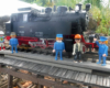 several model figures in front of a black steam engine