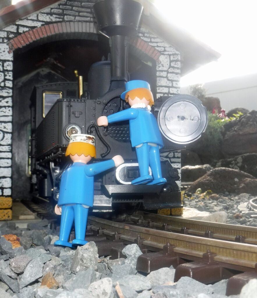 two figures in front of black model steam engine