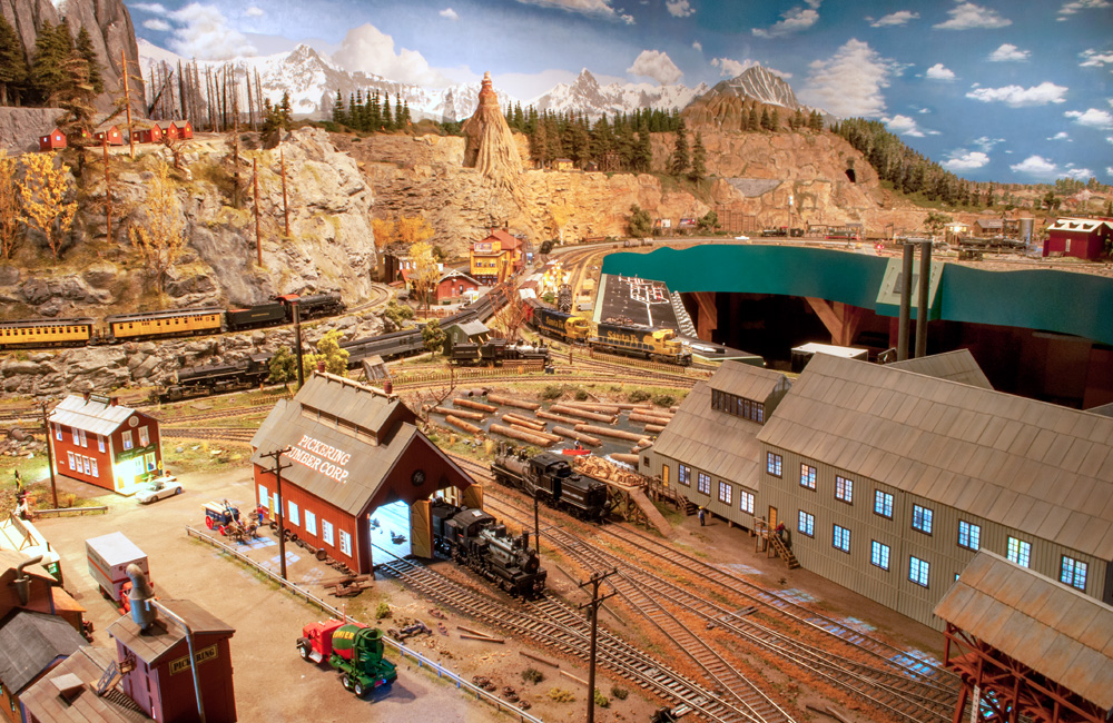 A sawmill is front and center in this long view over a model railroad layout