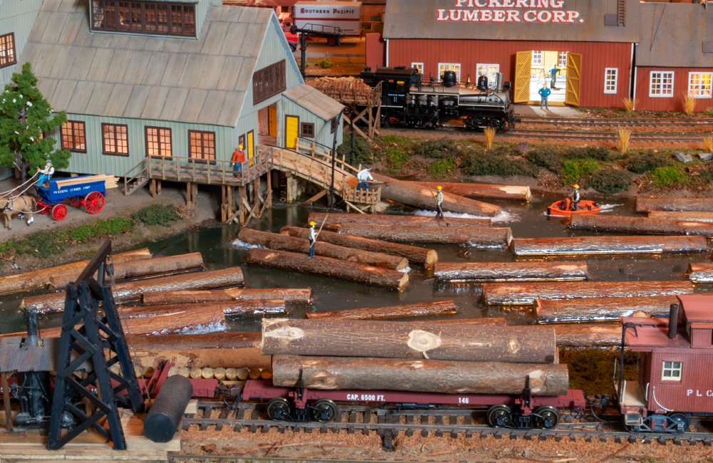 Logs are hoisted from a mill pond up an incline and into a sawmill