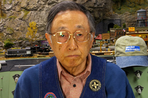 Head-and-shoulders photo of man sitting in front of a model train layout