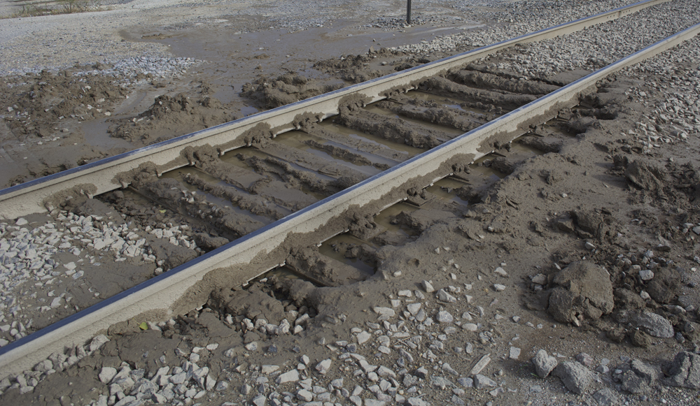 Color photo showing mud-covered ties and standing water. 