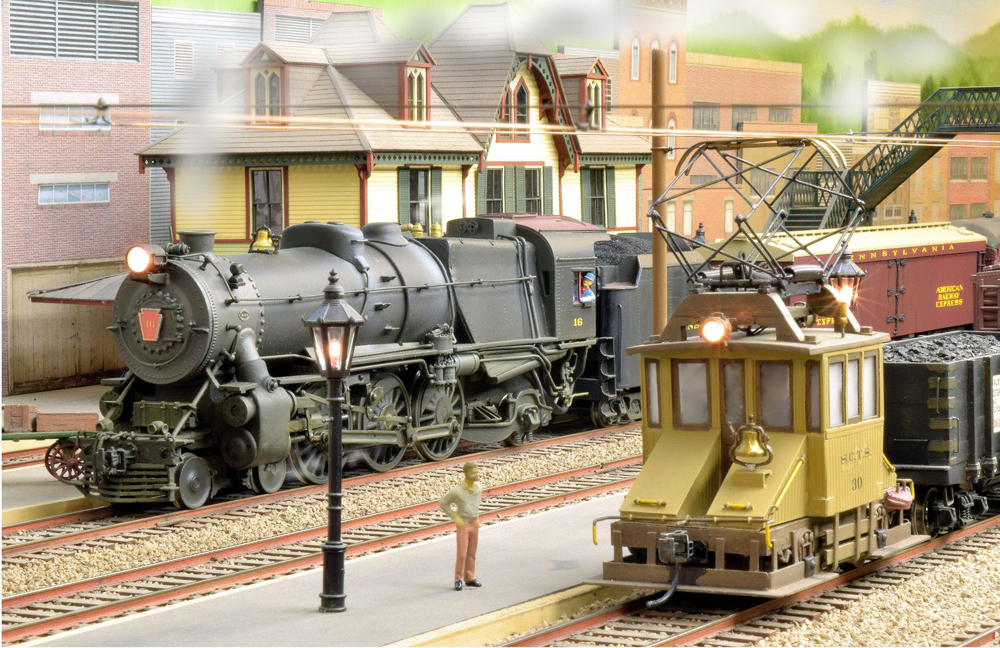 model steam engine passes through town on train layout