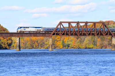 Amtrak train going over water on bridge in fall