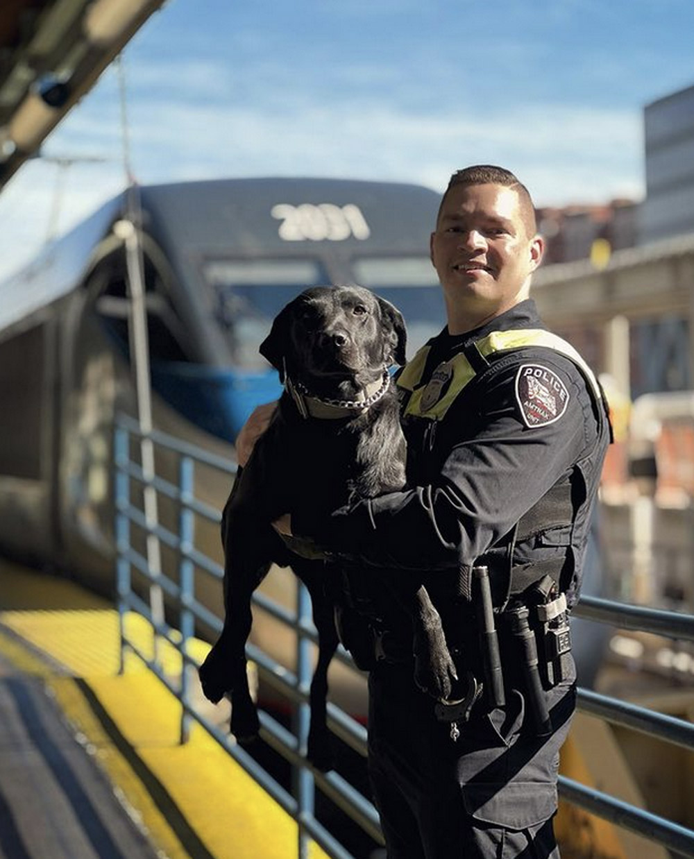 police officer holding his black lab