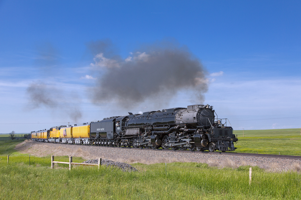 Big Boy steam locomotive rounds curve on a sunny day.