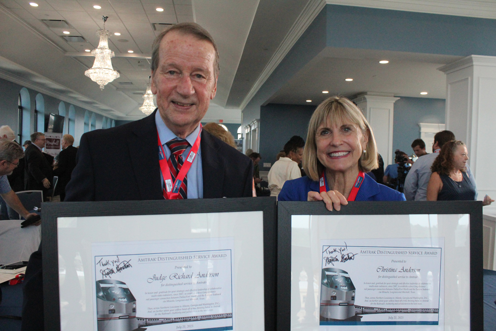 Man and woman holding framed awards