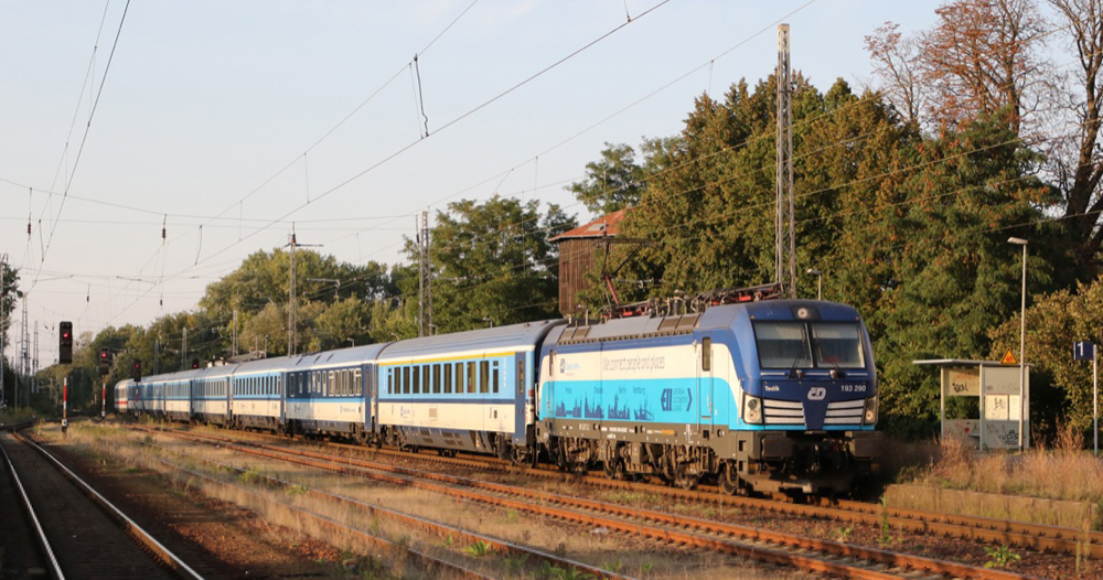 Blue and white passenger train pulled by electric locomotive
