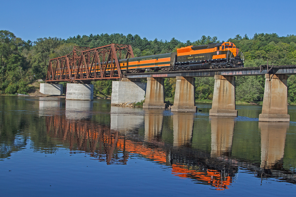 Green and orange diesel and matching passenger cars on bridge