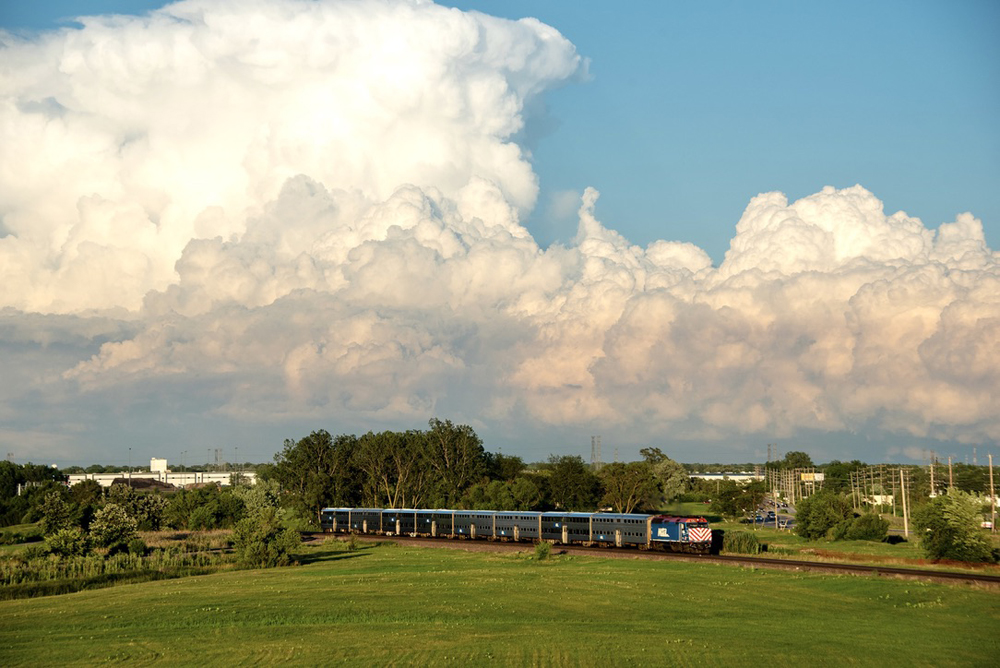 Commuter train with massive thunderstorm in distance