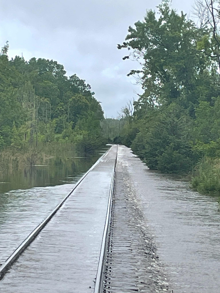 Flood waters obscuring rail line except for top of rails.