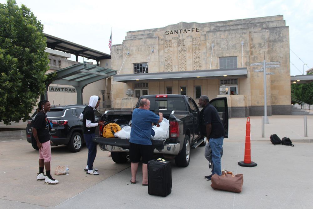 People standing around pickup truck outside train station