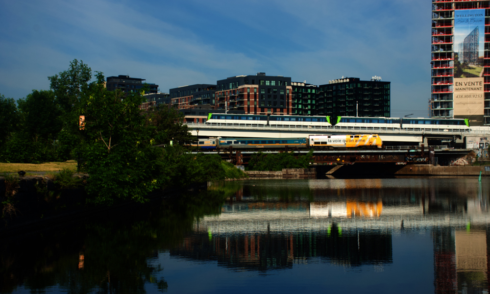 Light rail train and passenger train pass near body of water