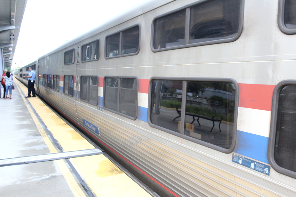 Exterior of sleeping car with two levels of windows at station platform.