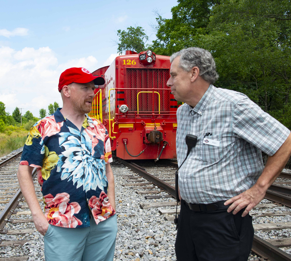 Two men standing in front of red locomotive