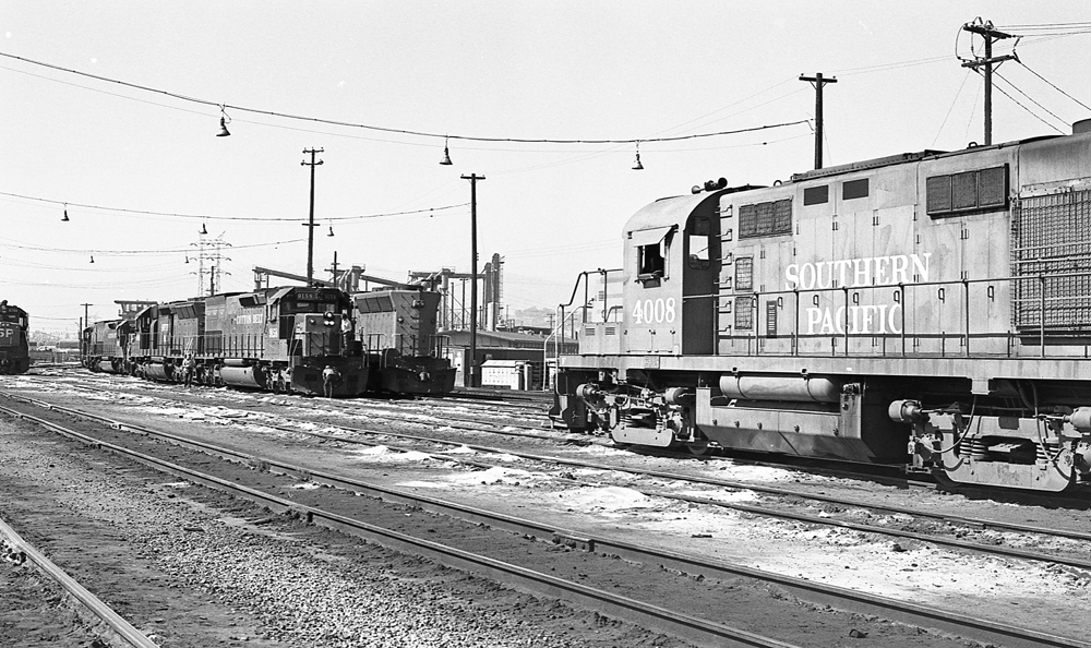 Black and white photo of Alco locomotive among EMDs at rail yard