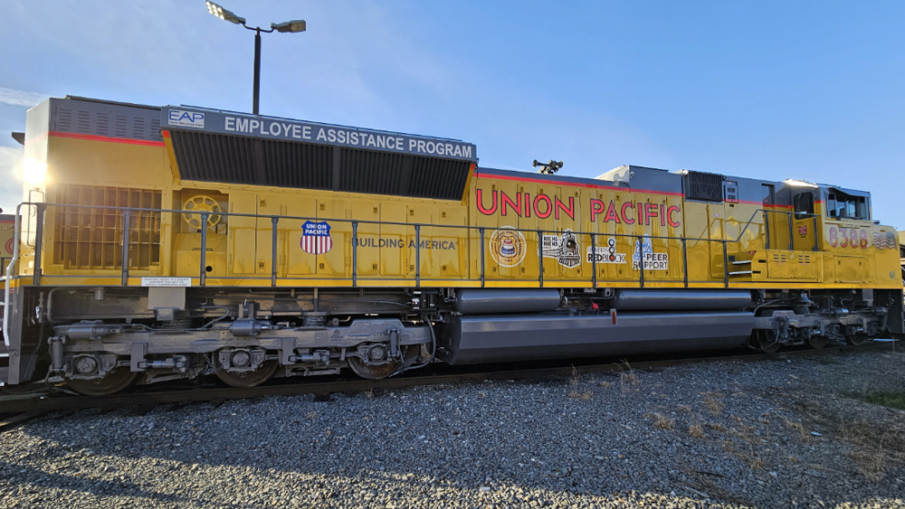 Side view of yellow locomotive with five logos added to usual UP lettering