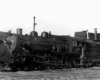 Steam locomotive in front of shop building