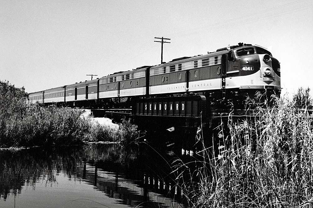 Streamlined passenger train crossing waterway on bridge
