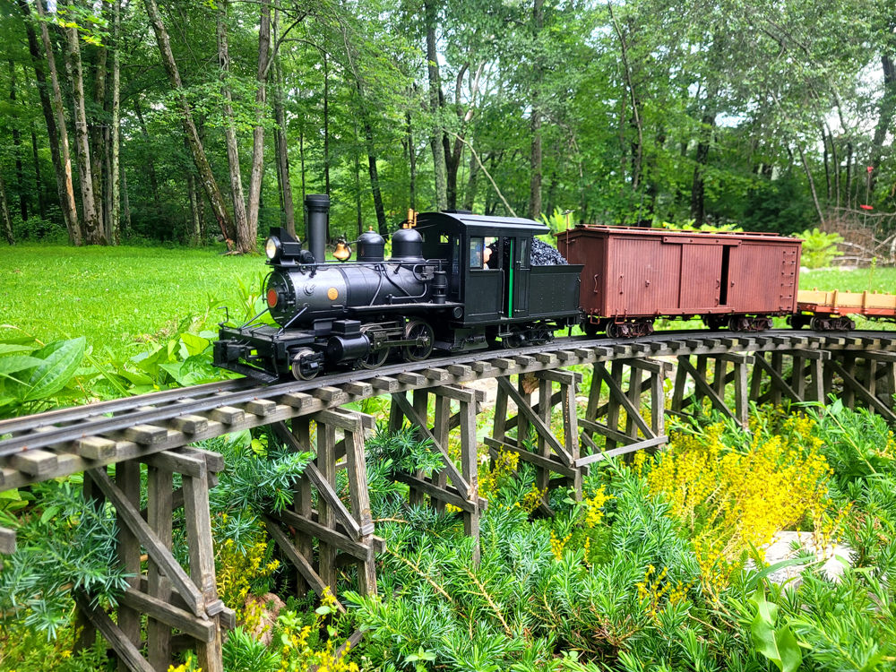 model steam engine with train crosses wood trestle