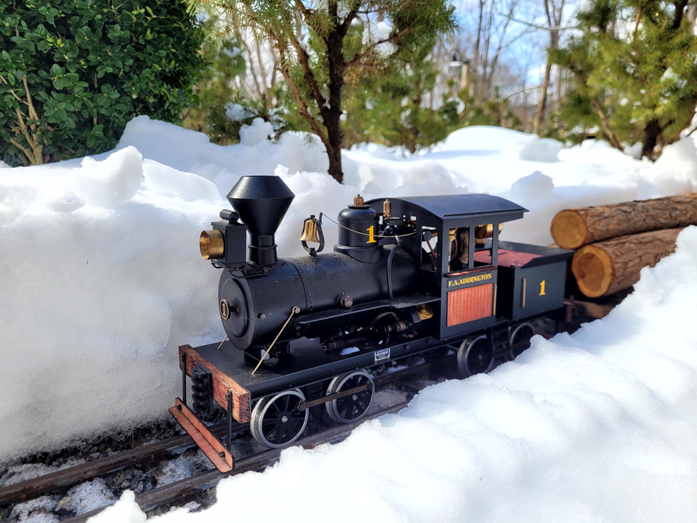 model train with load of logs on track with snow surrounding it