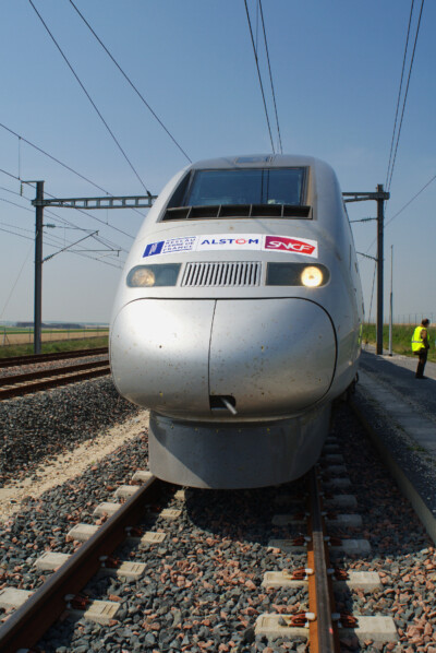 Silver streamlined high-speed train standing on a siding.