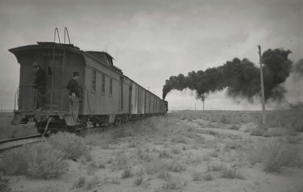 Steam powered train going away with a combination caboose-coach-baggage car on the back end.