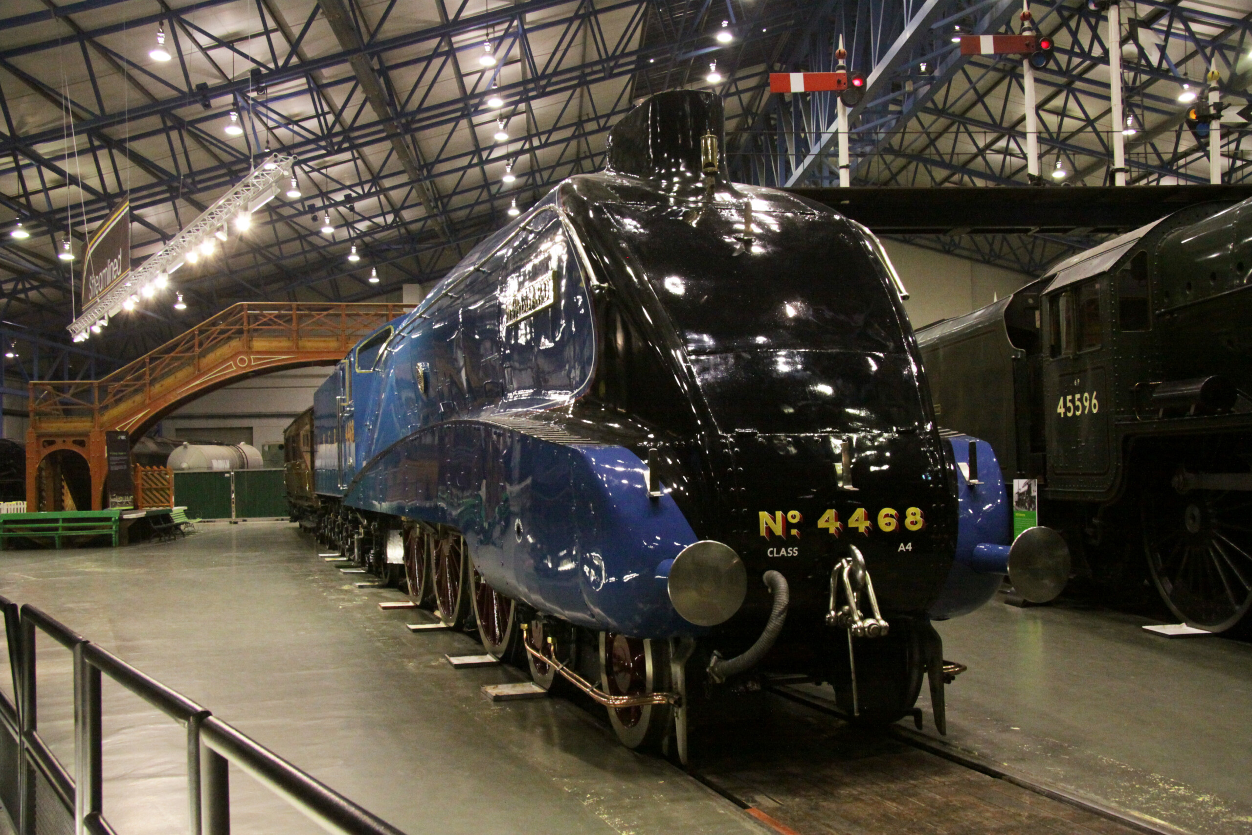 Blue and black aerodynamic steam locomotive in a museum hall