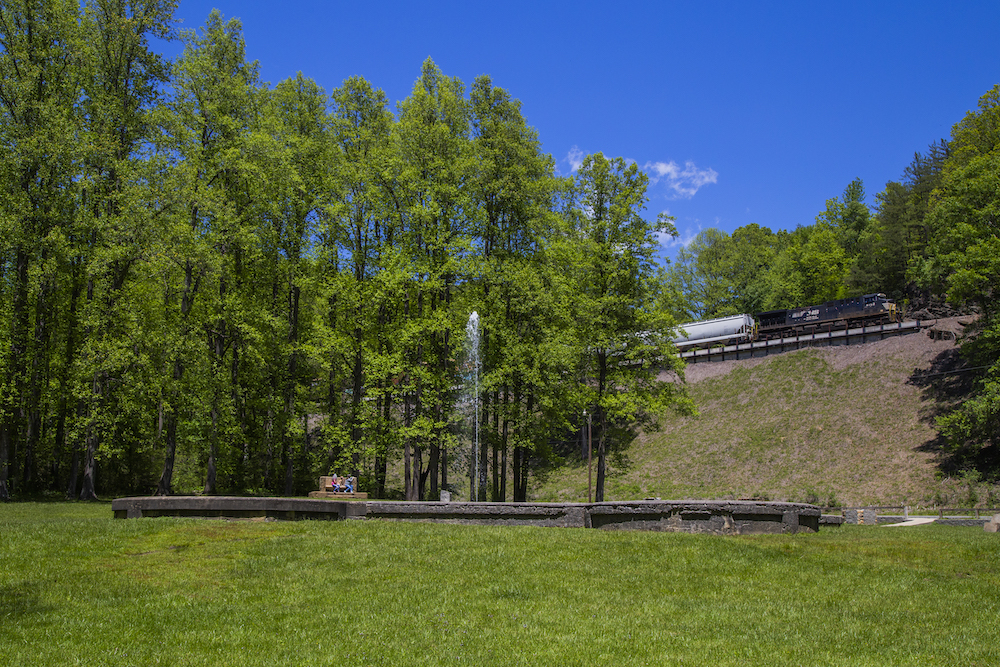 Freight train traversing loops with a geyser in the forefront.