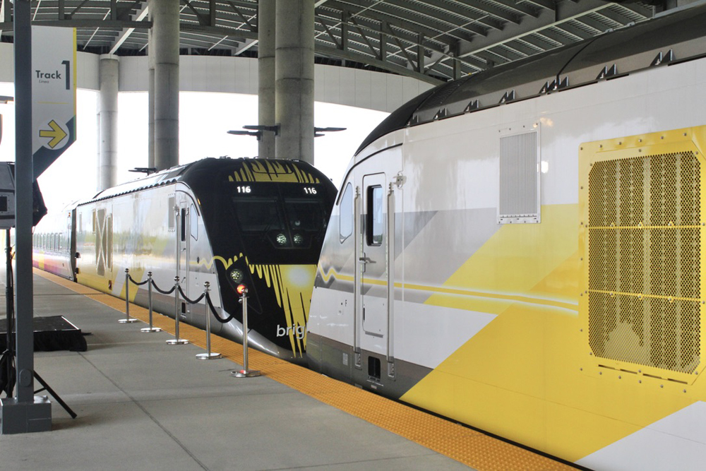 Two yellow and white trainsets nose to nose