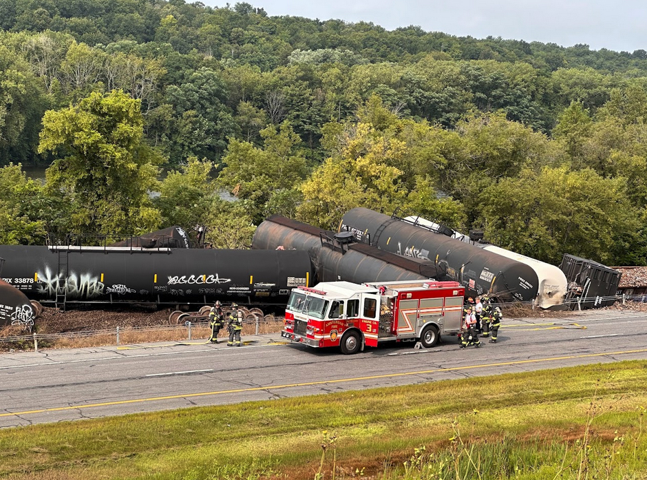 Fire truck next to derailed tank cars on closed highway