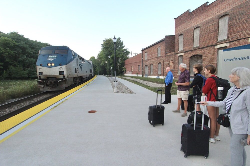 People standing on station platform as train approaches