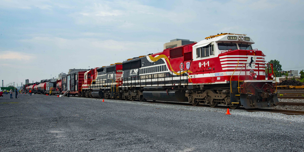 Red, white, and black locomotives with train of equipment for training first responders